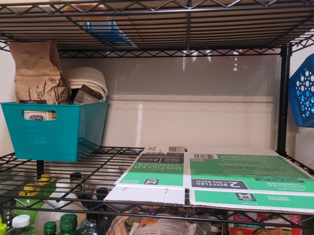 Almost empty shelf one side has cardboard on it the other side has a bin on it