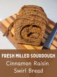 a loaf of bread on a cutting board with cinnamon sticks and a bread knife