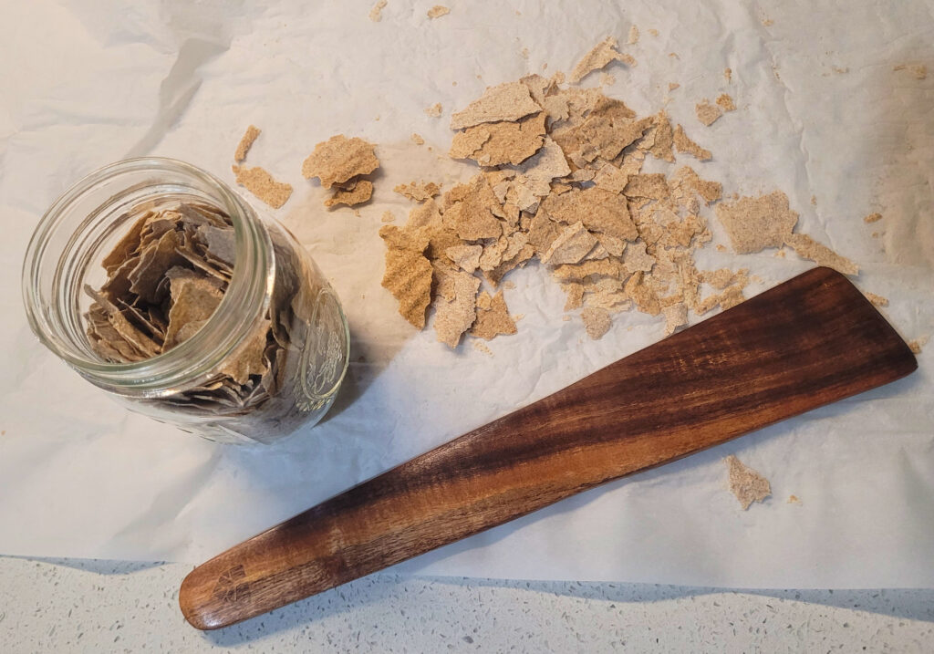Sourdough Starter Crushing counter with dried starter, parchment paper, a jar and a wooden spatula