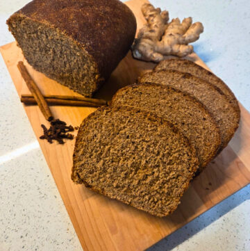 a loaf of sliced bread, a piece of ginger, cloves, and cinnamon sticks