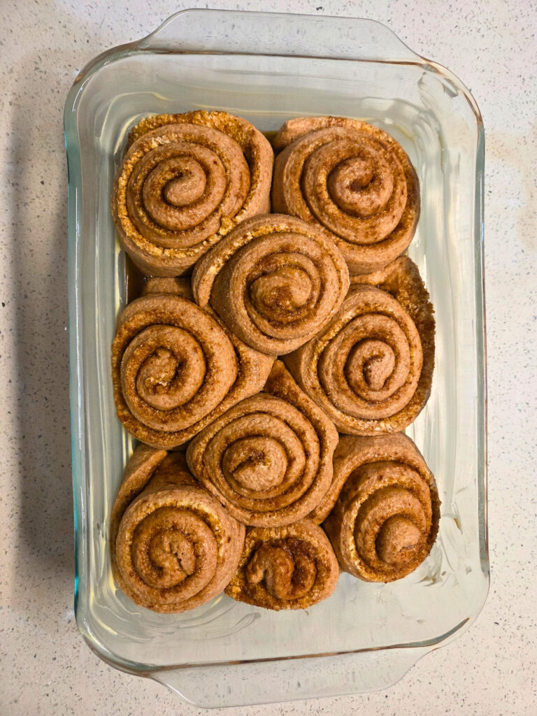 unbaked cinnamon rolls in a buttered pan