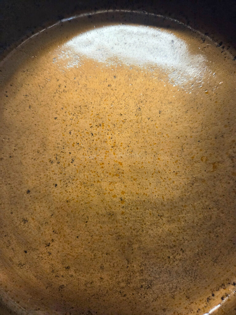 Over Oiled Pan - Seasoning and Cast Iron Pan - Edited a close up picture of a seasoned cast iron pan with brown spots on it