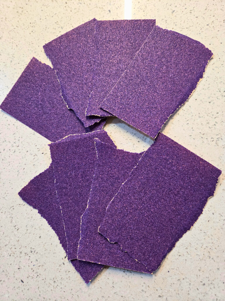 Rip Apart the 80 Grit Sand Paper - Resurface a Cast Iron Pan - Edited purple sand paper ripped up into 8 pieces