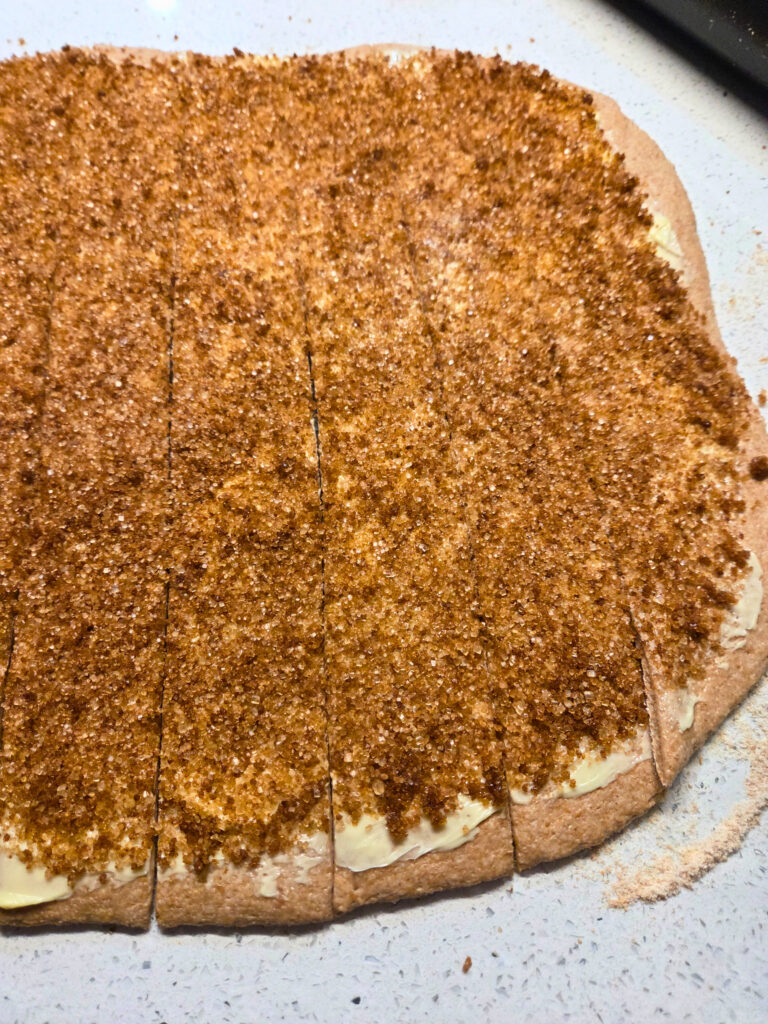 dough rolled out covered in butter and cinnamon and sugar, cut in 1.5 inch strips