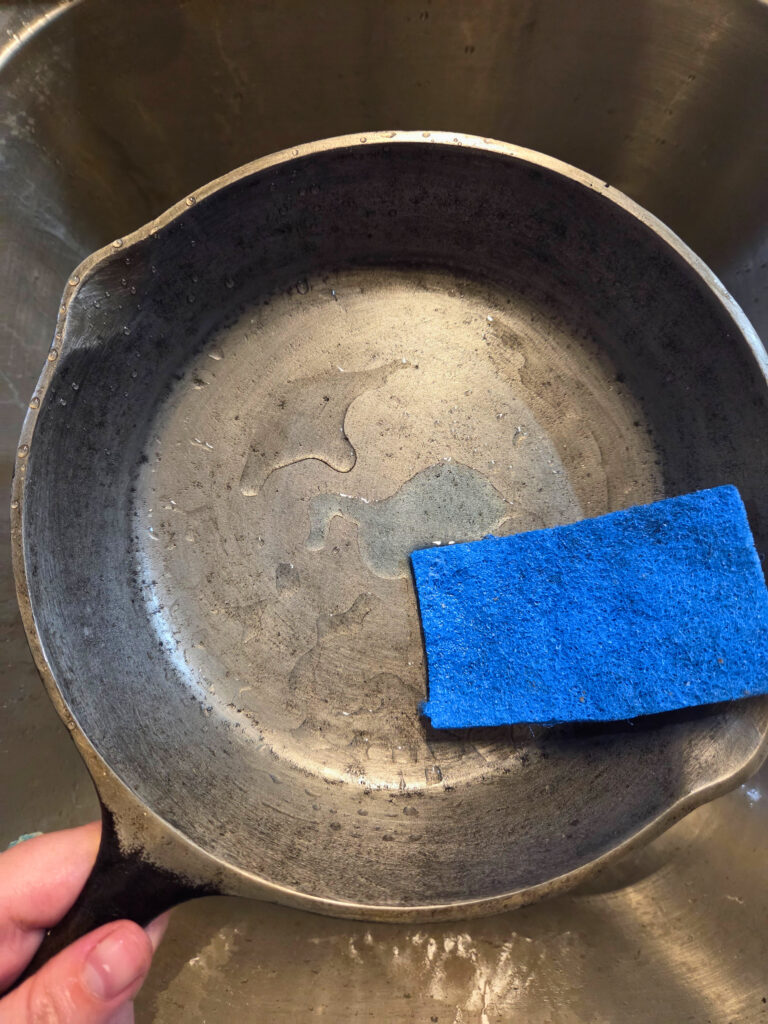 Wash with Water and Soap - Resurface a Cast Iron Pan a cast iron pan with soap, water, and a scrub pad
