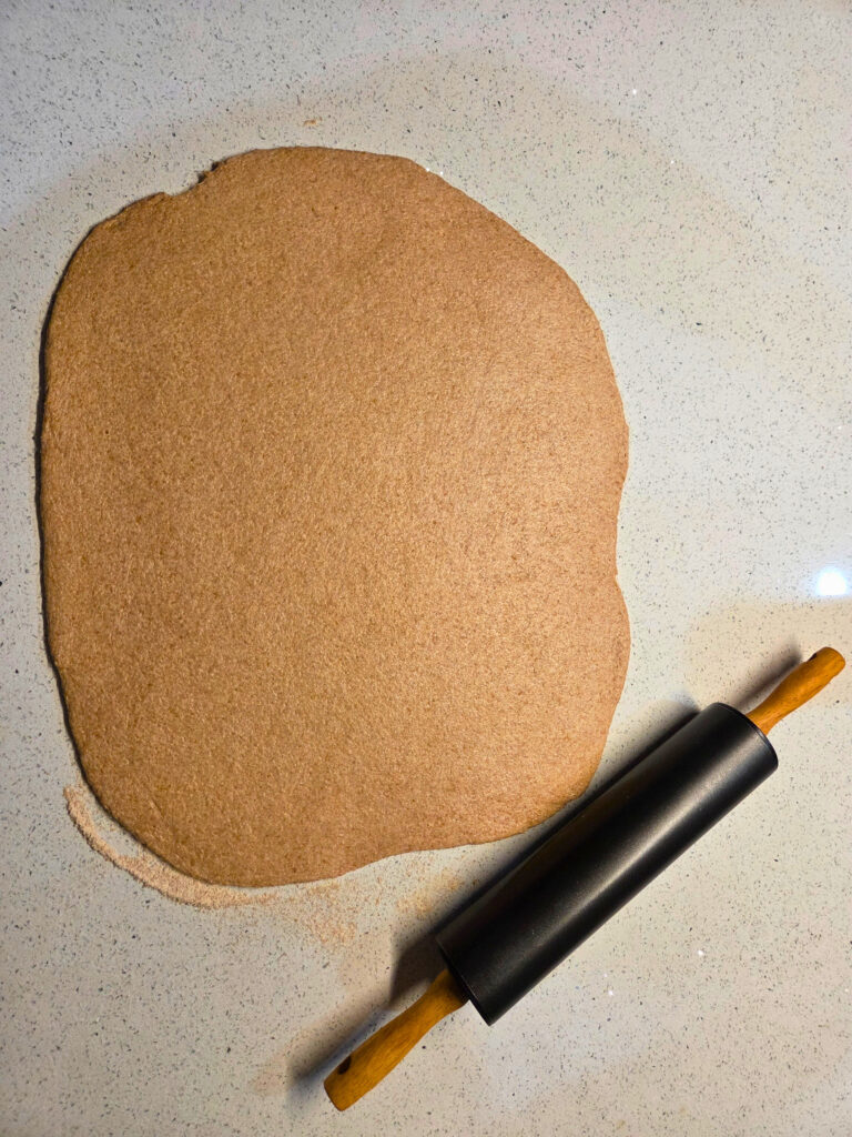flat dough rolled out next to a rolling pin
