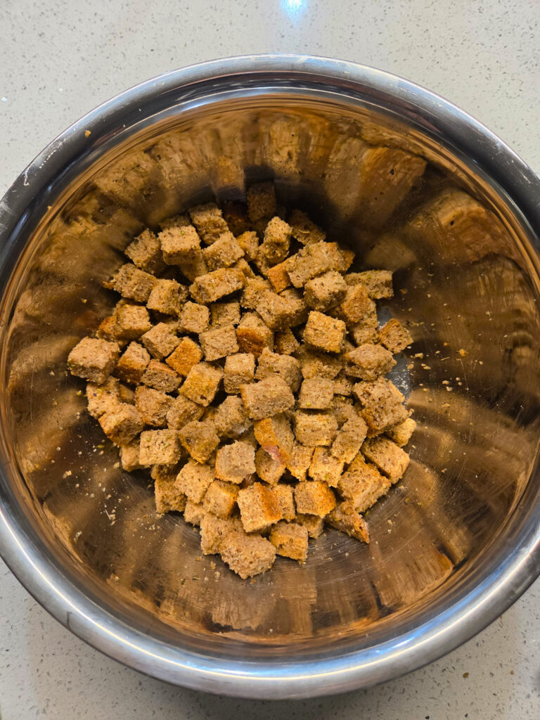 a bowl of cubed bread mixed with seasonings and oil