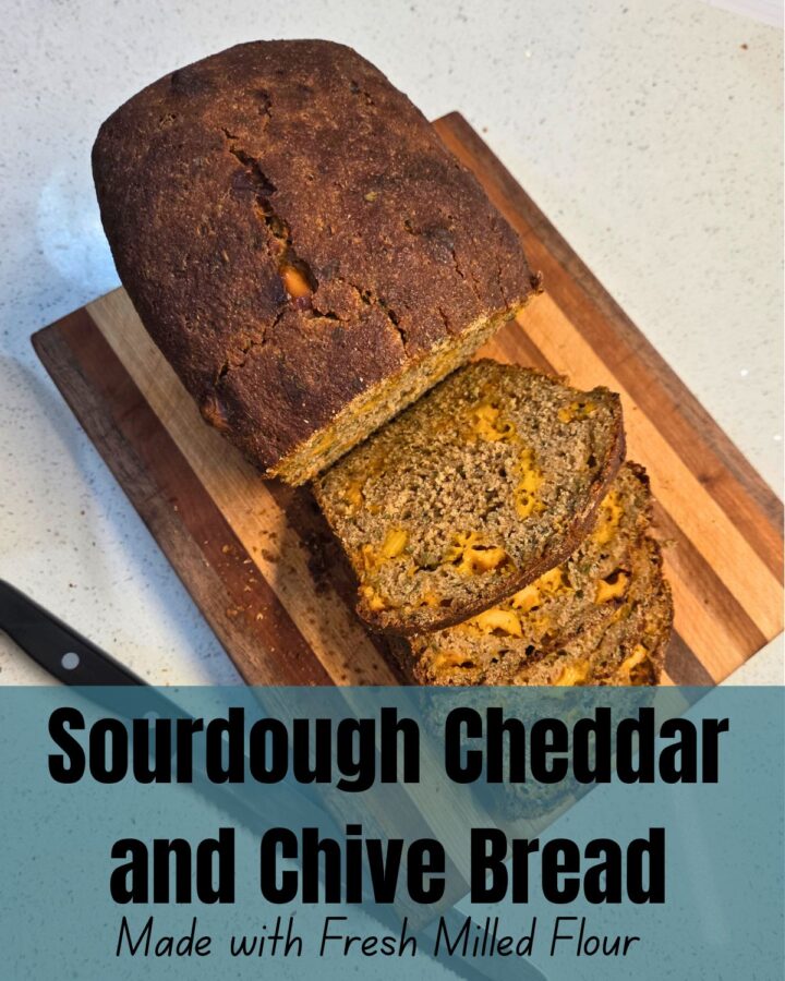 a partially sliced loaf of bread on a cutting board, next to a bread knife