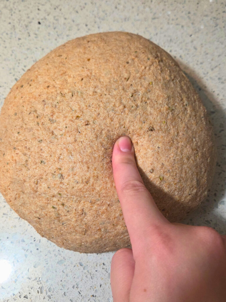 a ball of dough with a finger poking into it